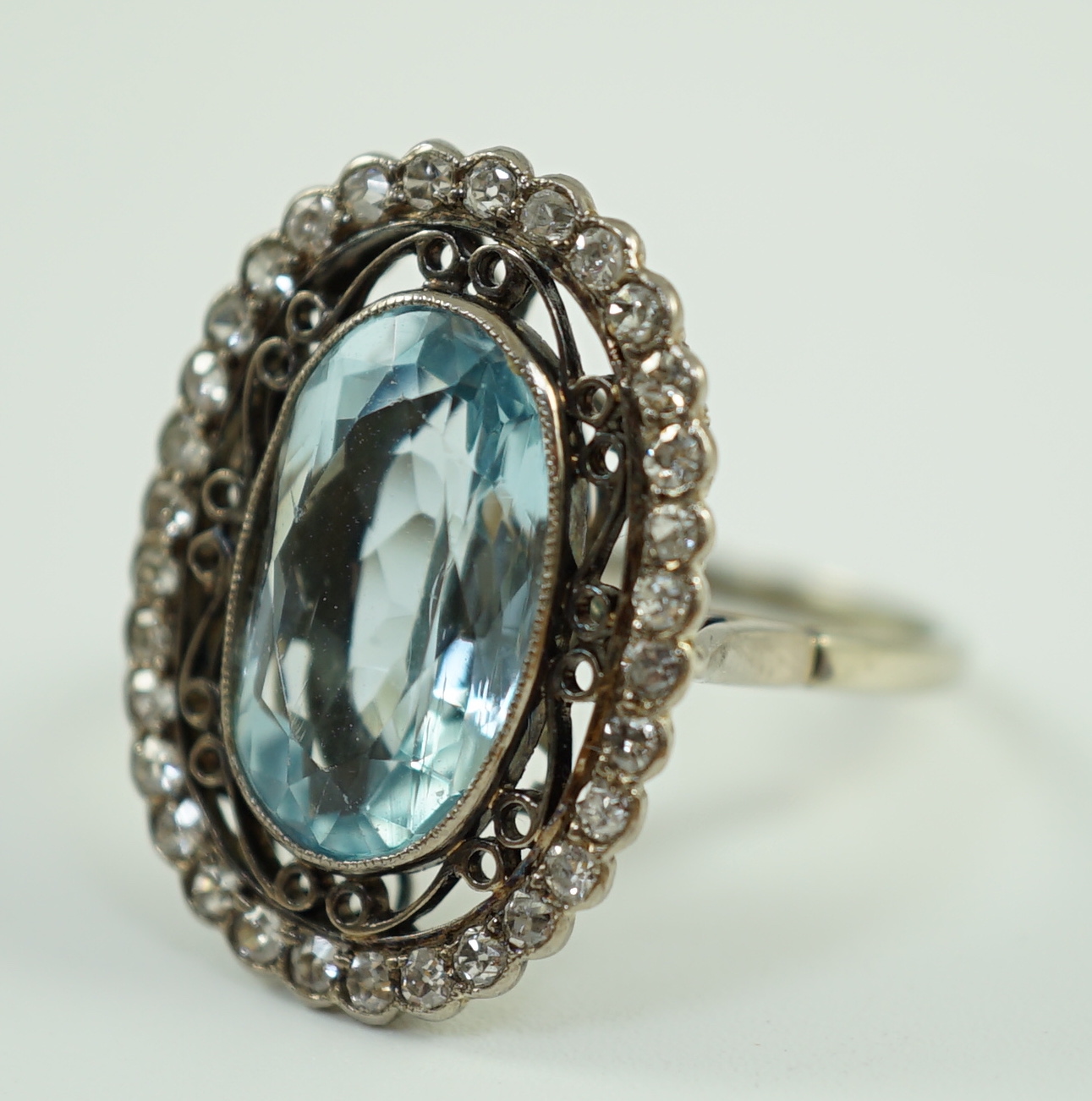 An 18ct white gold and single stone oval cut aquamarine set dress ring, with brilliant cut diamond set border